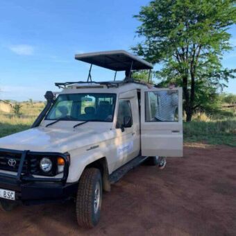 Safari auto van Droomreis Tanzania. Het dak is omhoog en een iemand stapt net de auto in