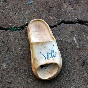 Slipper van hout met de tekst smile. Reiservaring Tanzania