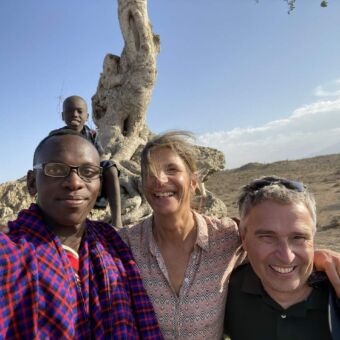safari Tanzania reiservaring. Twee gasten en hun Masai gids met daarachter op een boom een jongetje die een selfie maken