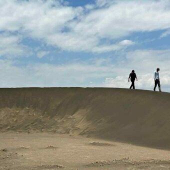 Wandelen over de verplaatsende zandduin bij Shifting Sands Eigenaren Wilma en Martin van Droomreis Tanzania boven op de shifting sands in Tanzania. Het zwarte zand van de het heuveltje verplaats zich door de wind steeds verder