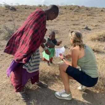 Reiservaring van gasten van Droomreis Tanzania. Vrouw met een Masai kindje en een Masai man die in gesprek zijn