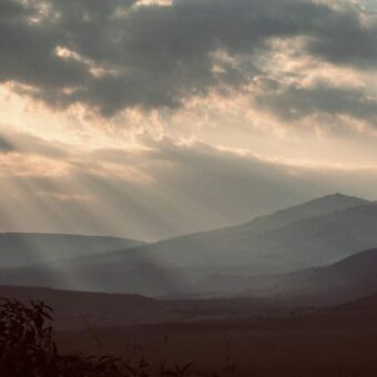 zonnestralen door de wolken en ochtenmist bij ngorongoro krater