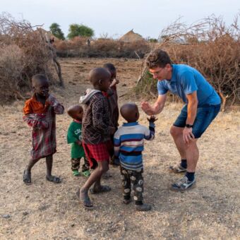 man geeft box aan Tanzaniaanse kindjes