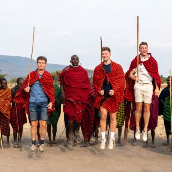 reizigers in traditionele kleding van de Masai springen met de Masai
