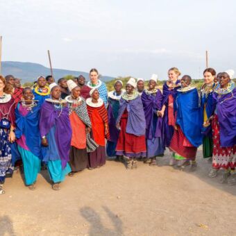 gasten in traditionele kleding van de Masai staand tussen een grote groep Masai