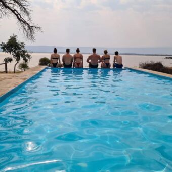 gasten van droomreis tanzania die op de rand van hun zwembad zitten en uitkijken over Lake Manyara