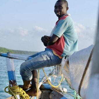 Jongen zittend op de giek van een Dhow op Zanzibar