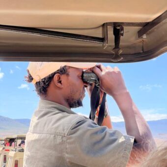 gids met verrekijker die probeert een dier te spotten