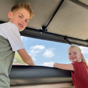 Kinderen staand op de stoelen in de safariauto