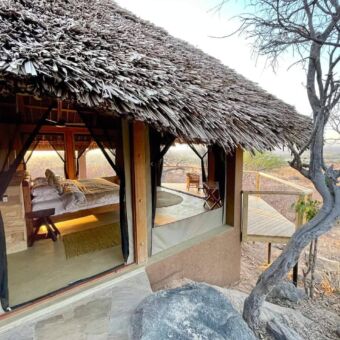 Luxe suite met remain van gaas een dak van traditioneel riet. Je kijkt naar binnen waar een groot bed staat