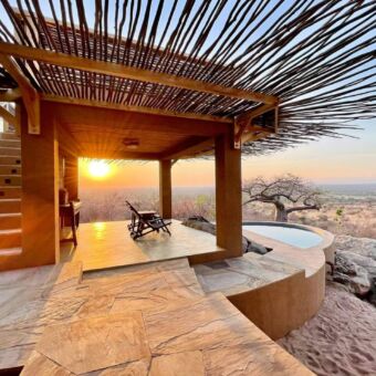 Overdekte veranda, gedecoreerd met takken rondom met daarvoor een plunje pool en er boven een topdeck