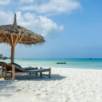 Rieten parasol met daaronder een ligbed op het strand van Pemba eiland