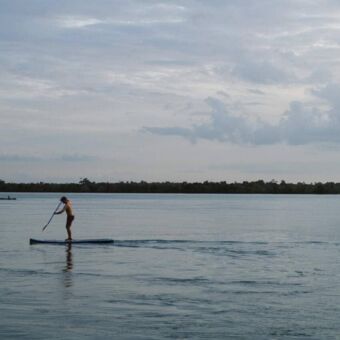 Man op een paddleboard op het azuurblauwe water van de Indische Oceaan in Tanzania
