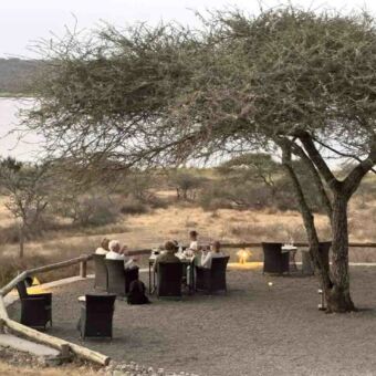 Terras midden in de natuur met mensen rond een tafel in Ndutu Tanzania