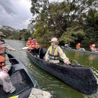 familie in verschillende kanoboten op Lake Duluti in een groen omgeving