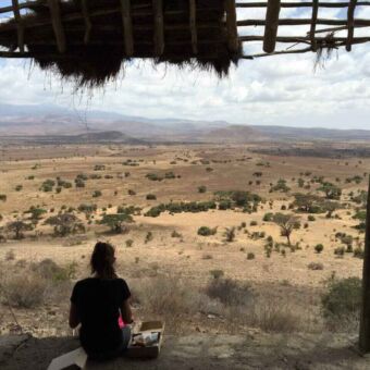Meisje zit op de rand en kijkt uit over de vlaktes van Enduiment