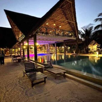 Lodge op Zanzibar met een rieten kap en mooi verlicht bij avond