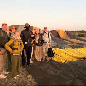 Warm aangeklede familie voor een leeggelopen ballon na een ballonsafari oboven de Serengeti