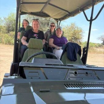 vier vrouwen in een open safari auto die lachen