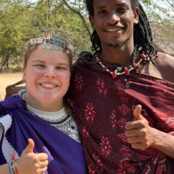 Vrouw met Masai man met lang haar. Beide hebben de duim omhoog