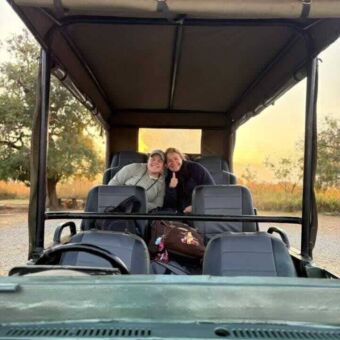 Twee vrouwen die lachten en je aankijken in een open safariauto