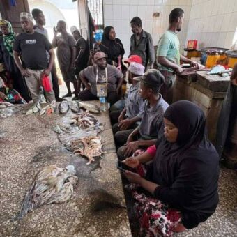 Groepje mannen en vrouw aan een grote tafel waarop vis ligt die net schoongemaakt is