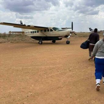 Op de airstrip in Mikumi lopen mensen naar hun vliegtuigje