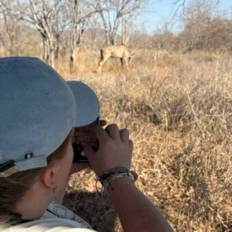 vrouw die een dier spot vanuit de safari auto en daar een foto van probeert te maken