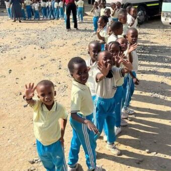 Zwaaiende groep kleine kinderen in een schooluniform onderweg naar Mikumi