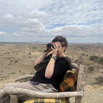 Vrouw zittend in een stoel met een verrekijker de omgeving af speurend