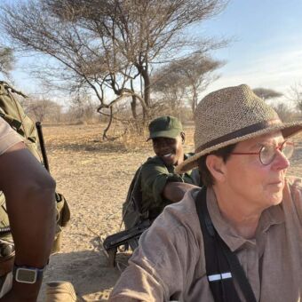 Vrouw en gids zittend op de grond speurend naar wil tijdens een wandelsafari